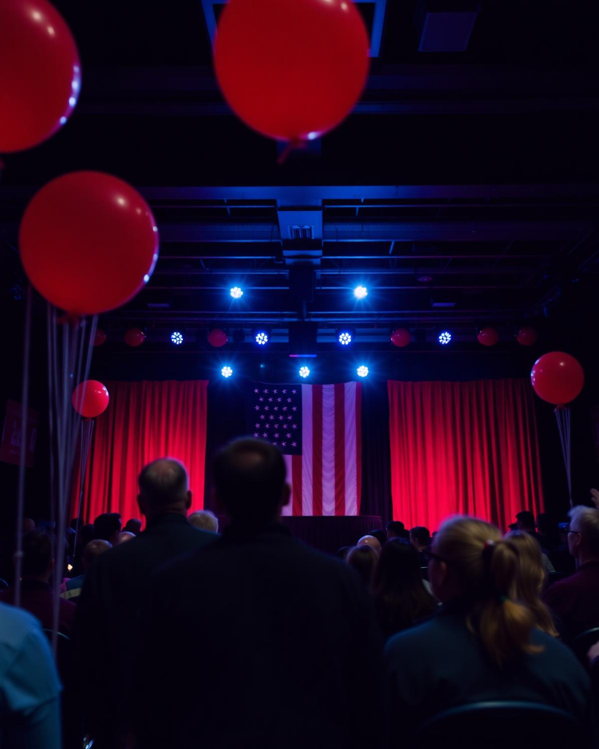 Election night watch party hall with stage lights and balloons.